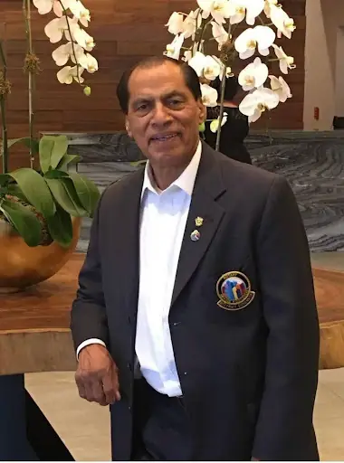 Dr. Manzoor R. Massey in a hotel lobby beside orchids